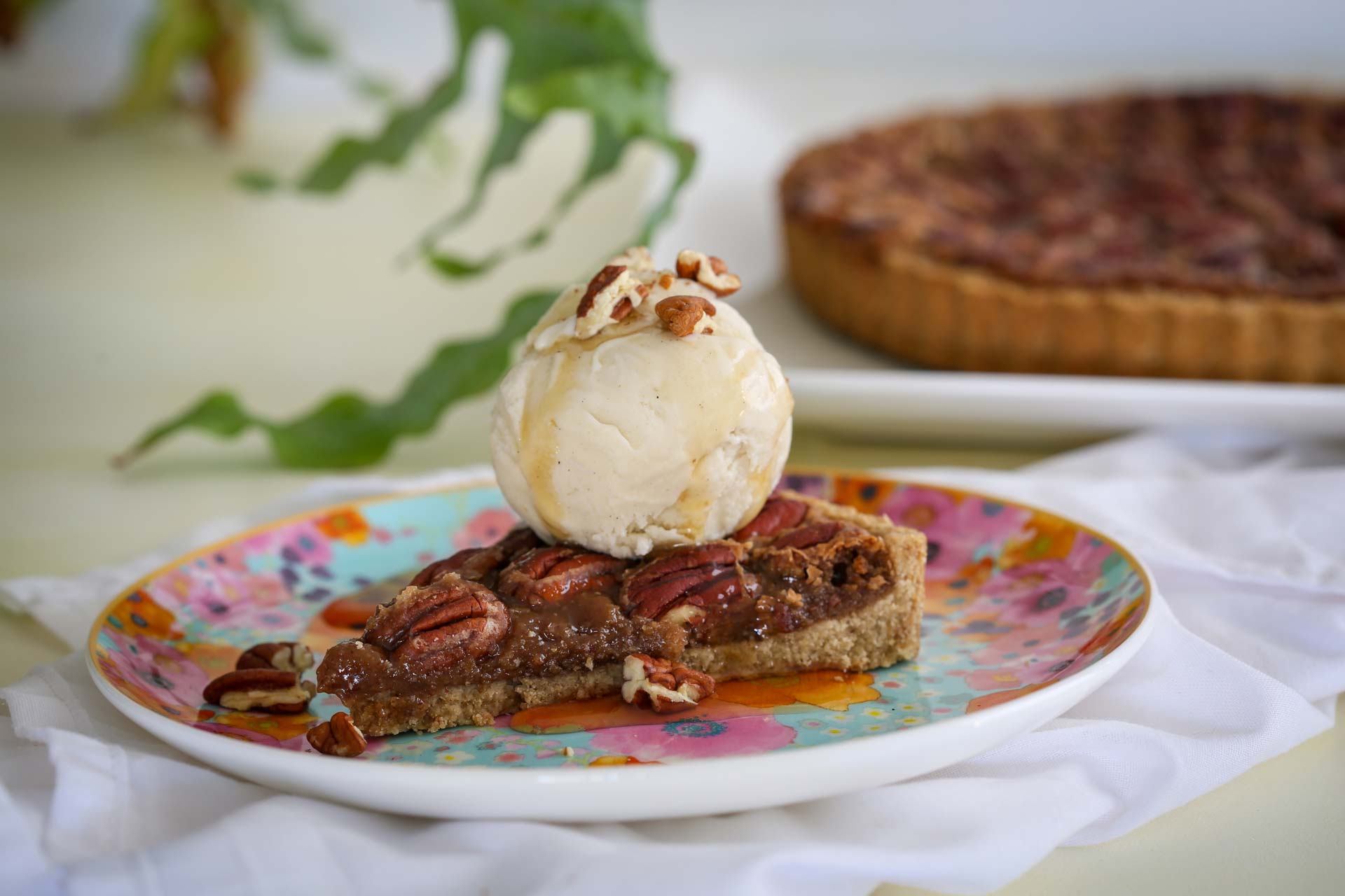 Ooey gooey maple pecan caramel pie slice topped with a smooth and decadent oat milk vanilla bean ice cream